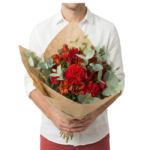 Bouquet Bea de flores vermelhas intensas com folhagens de eucalipto, embalado em papel kraft sofisticado, ideal para presentear com elegância e personalidade.