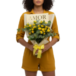 Mulher segurando bouquet de mini-rosas amarelas premium com eucalipto, embalado em papel bege com laço amarelo, coleção AMOR da Une Fleur dans la Ville