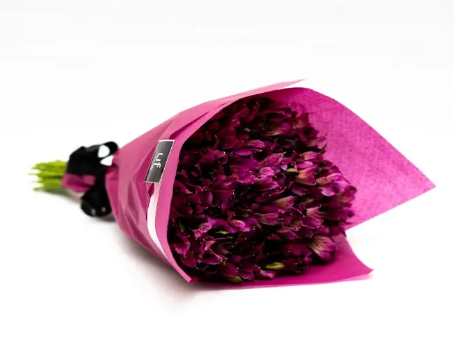 Bouquet de astromélias rosas, envolto com papel da mesma cor e laço preto.
