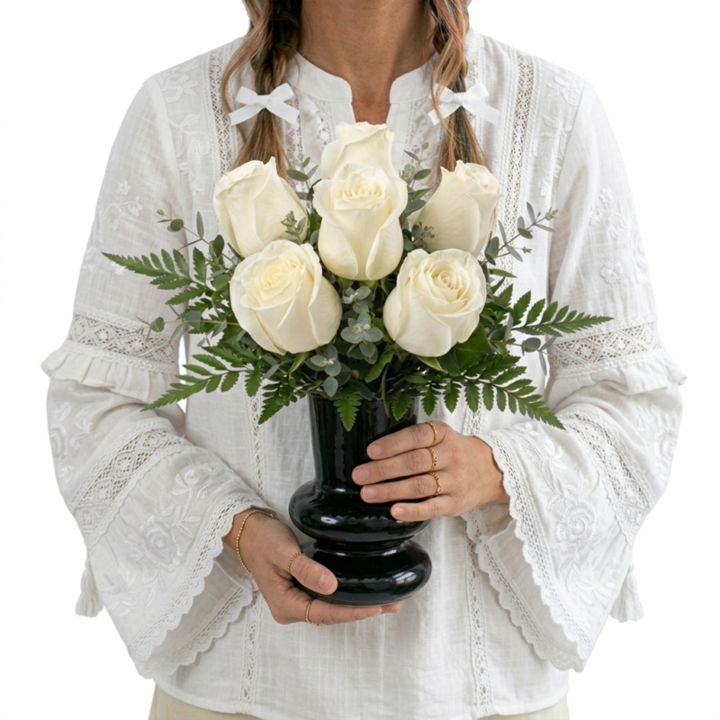 Arranjo de rosas brancasem vaso preto com folhagens verdes elegantes