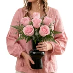 Arranjo de rosas cor-de-rosa em vaso preto com folhagens verdes elegantes