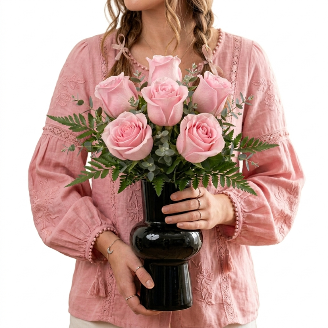 Arranjo de rosas cor-de-rosa em vaso preto com folhagens verdes elegantes