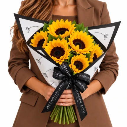 Buquê de girassóis amarelos Lily Rose com embalagem branca de bordas pretas e laço personalizado Une Fleur Dans La Ville. Flores frescas com entrega em São Paulo.