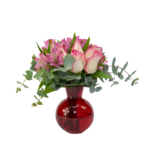 Arranjo de flores cor de rosa com folhagens verdes em vaso de vidro vermelho brilhante, ideal como presente romântico e elegante para ocasiões especiais.