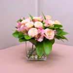 Arranjo elegante de rosas champagne e astromélias rosa em vaso de vidro, ideal como presente romântico e refinado.