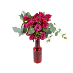 Arranjo de rosas pink com folhagens verdes em vaso de vidro vermelho brilhante, ideal como presente romântico e elegante para ocasiões especiais.