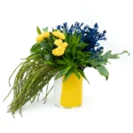 Arranjo tropical com rosas amarelas e flores azuis intensas em vaso vintage polonês de vidro amarelo da marca Alicja.