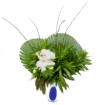 Arranjo floral de orquídeas brancas com folhagens verdes em vaso de vidro polonês branco com detalhe azul, usado para decoração de interiores ou presente de luxo.