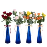 Quatro garrafinhas azuis com mini rosas vermelhas, rosadas, amarelas e laranja, com laços combinando, arranjadas lado a lado — Une Fleur dans la Ville.
