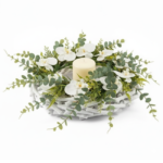 Guirlanda floral branca com flores delicadas, folhagens verdes e vela central decorativa, em base clara trançada, estilo sofisticado e minimalista.