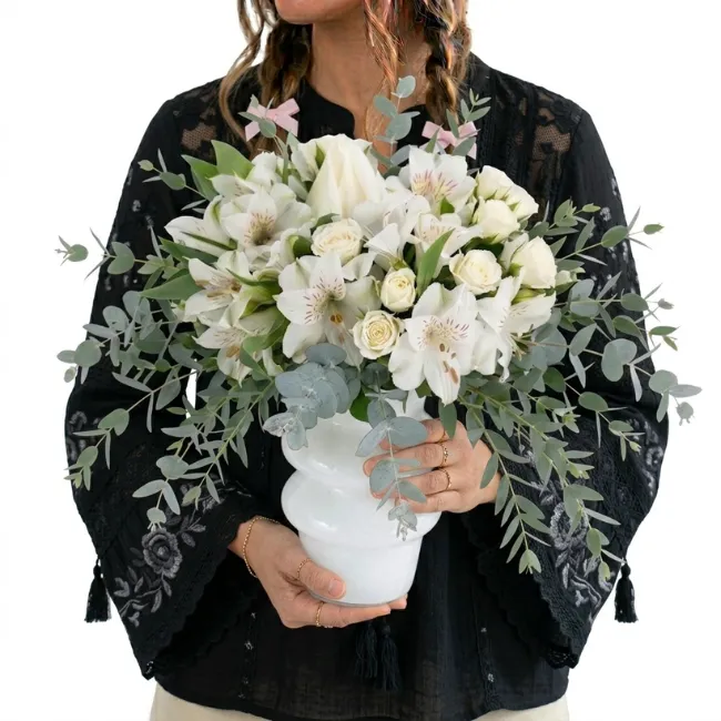 Arranjo elegante de flores brancas em vaso moderno branco com folhagens de eucalipto